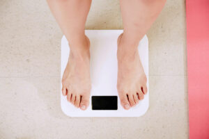 Person with obesity weighing himself on a scale